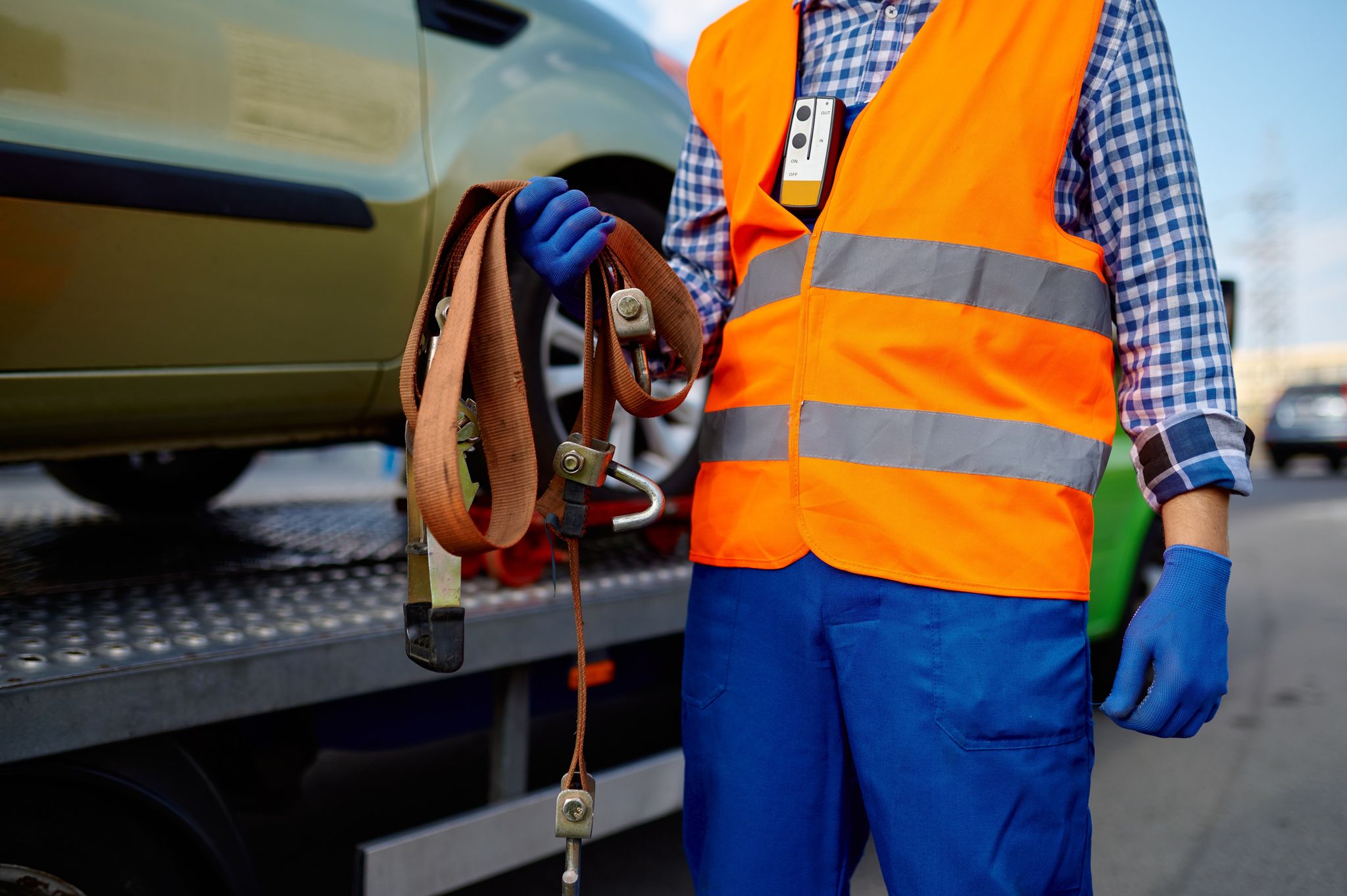 Male tow truck assistant holding belts for car fastening for safety transportation.